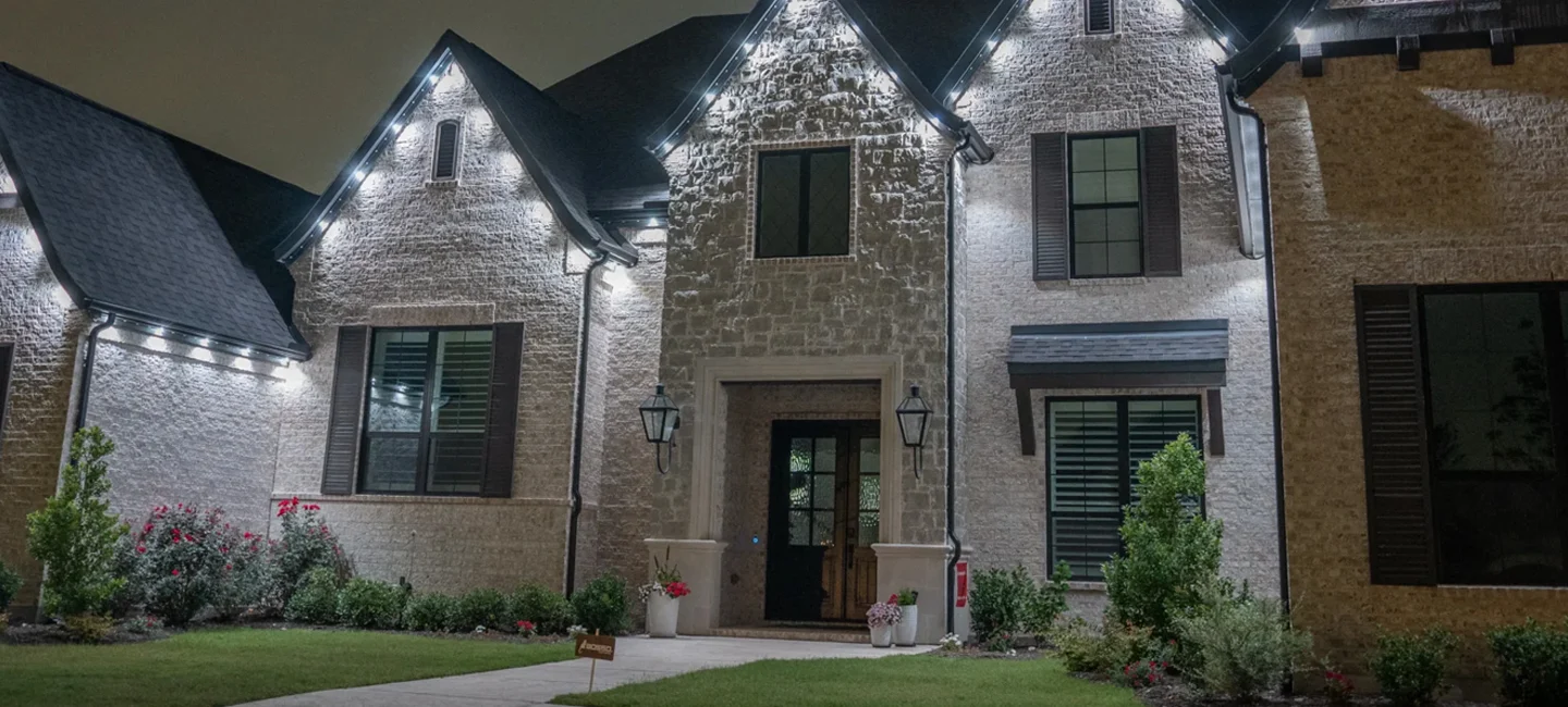A home at night lit with bright white permanent lights along the roofline